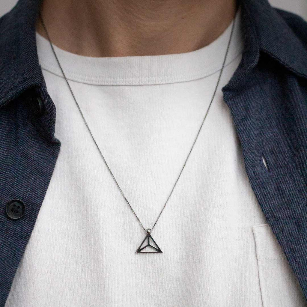 Yoga inspired rhodium necklace. The jewel stylises the Padmasana pose in an essential and geometric way. Sliding pendant for man.