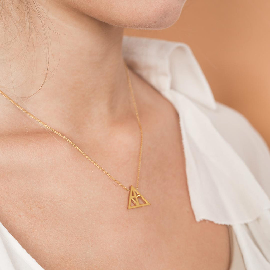 Yoga inspired gold necklace. The jewel stylises the Trikonasana pose in an essential and geometric way. Sliding pendant.