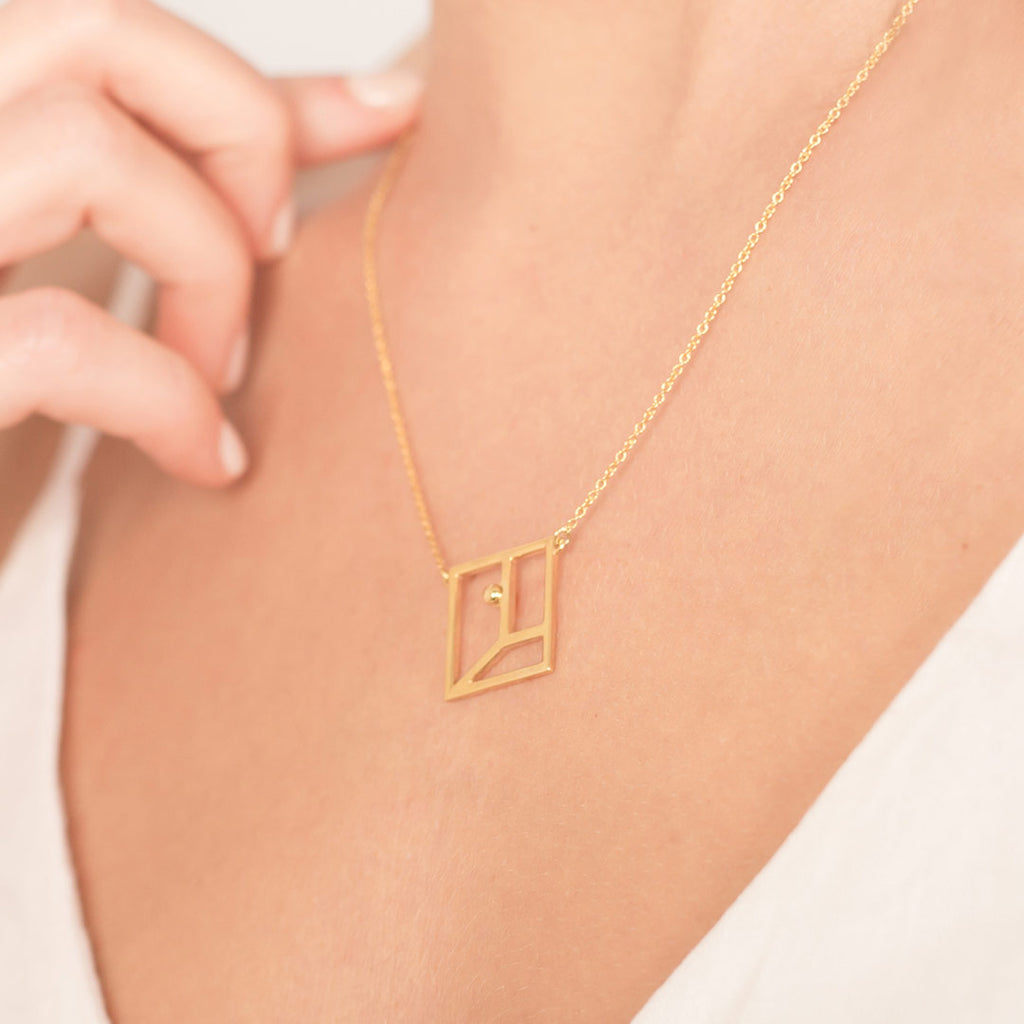 Yoga inspired gold necklace. The jewel represents the warrior one position. Essential and geometric style.