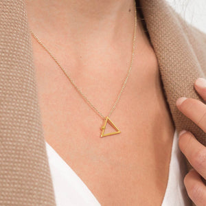 Yoga inspired gold necklace. The jewel stylises the Adho Mukha pose in an essential and geometric way. Sliding pendant.